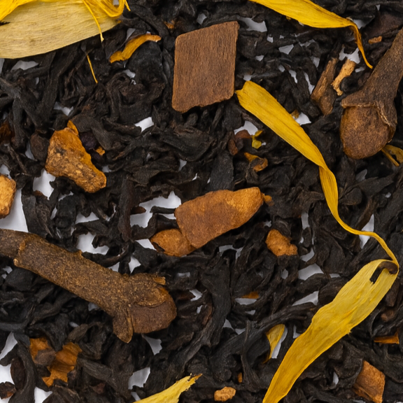 Close-up of black tea leaves with cinnamon sticks and yellow leaves on a white background